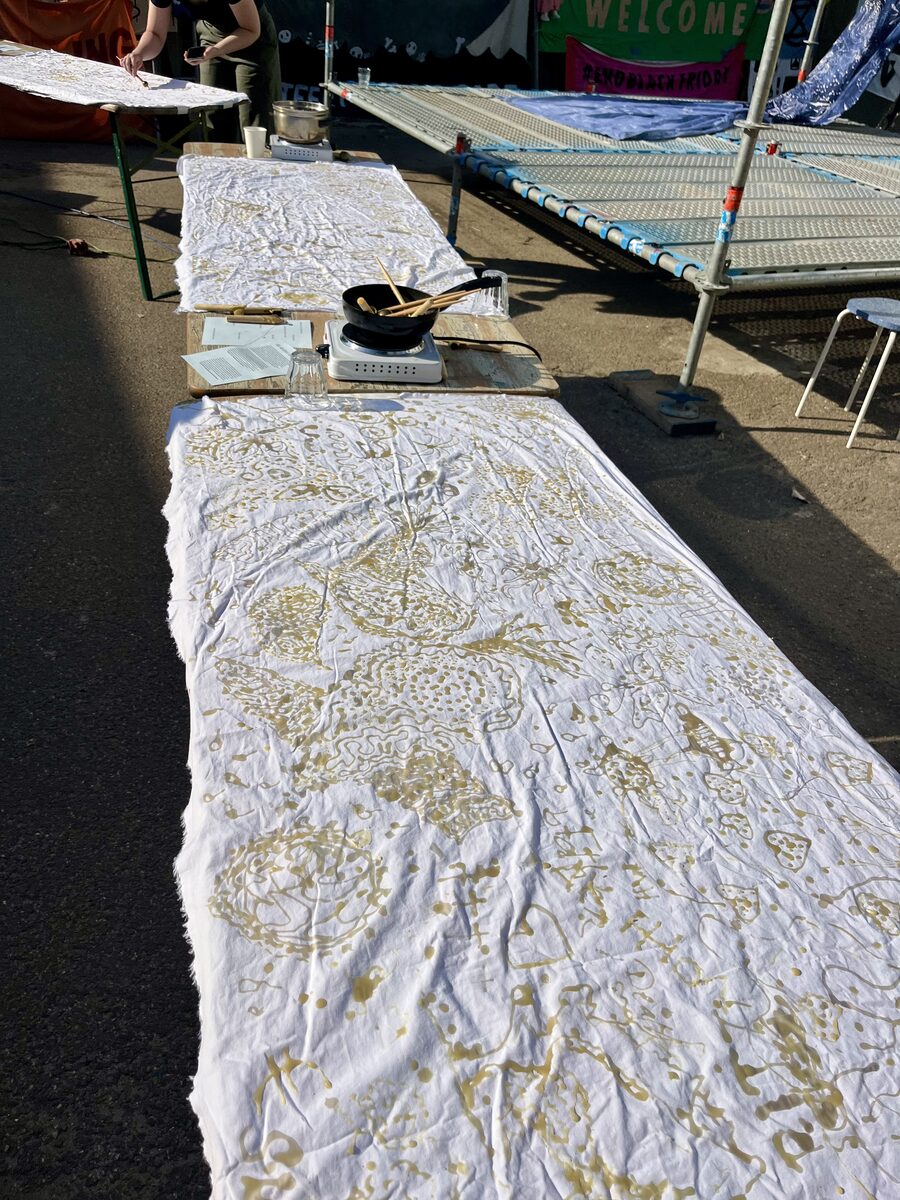 A long white cloth laid down the tables, covered end to end in wax drawings