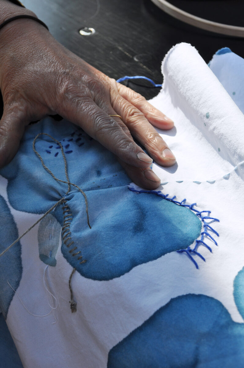 Hands embroidering blue batik fabric