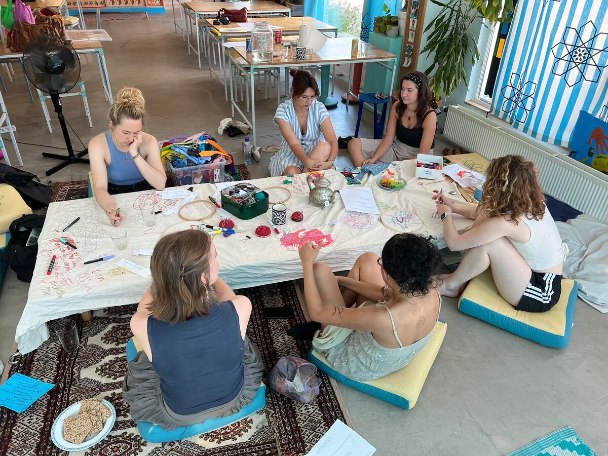 Participants embroidering together around a low table