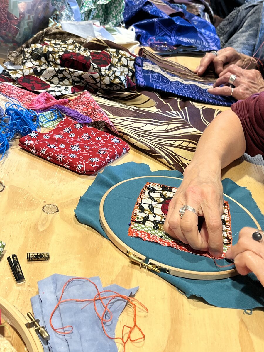Participants embroidering fabric pockets at the workshop table